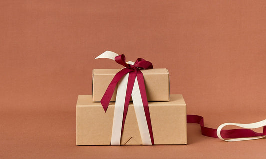 Two brown gift boxes with red and white ribbons on a brown background.