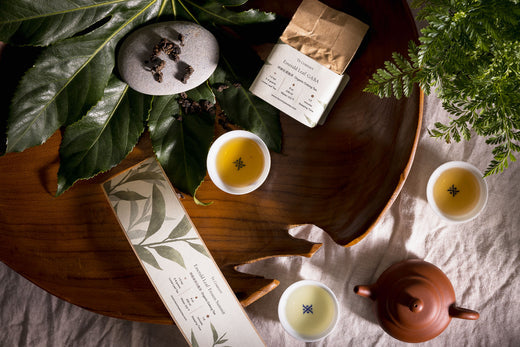 Tea set with leaves, cups, and packaging.