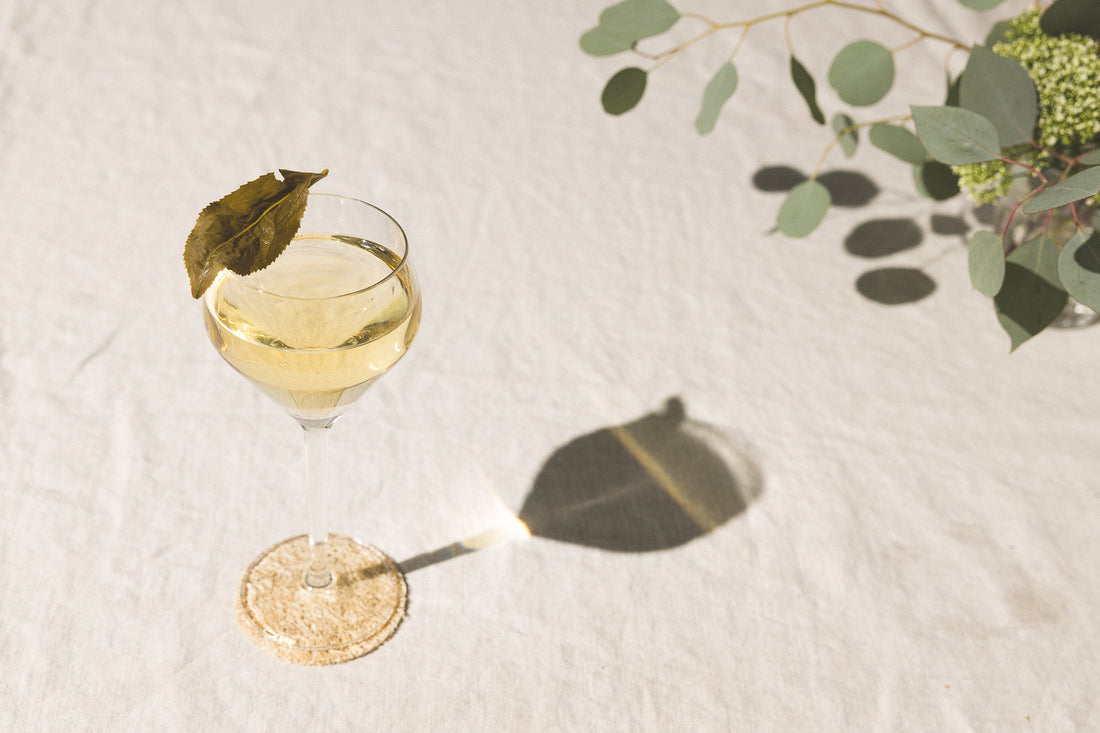 Glass of tea with leaf garnish on table.