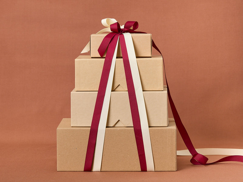 Stack of brown gift boxes with red and white ribbons on a brown background