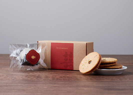A box of Choicest Wedding Tea with a package of tea bags and a plate of cookies.