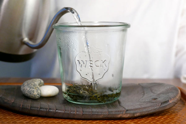 Pouring hot water into a Weck jar with loose leaf tea.