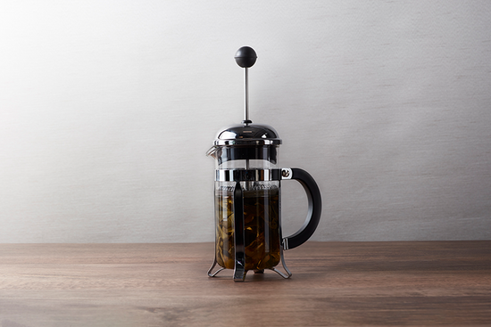 A french press with water and tea leaves inside.