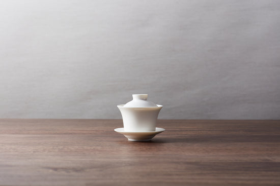 A white gaiwan teacup with lid and saucer.
