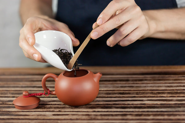 pouring loose leaf tea in teapot