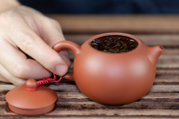 hand holding clay teapot
