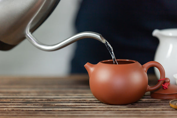 pouring water in clay teapot