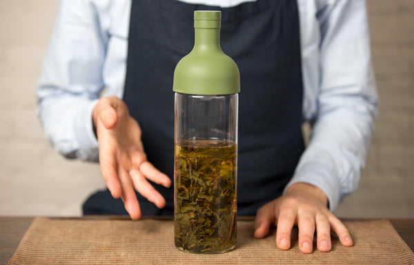 Cold brew tea steeping in a glass bottle with a green lid.