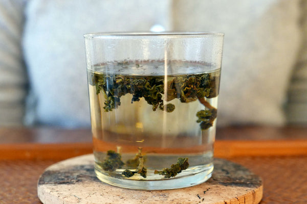 Tea leaves expanding while steeping in a glass cup.