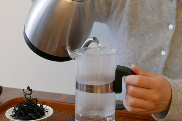 Pouring hot water into a glass pitcher to warm it up.