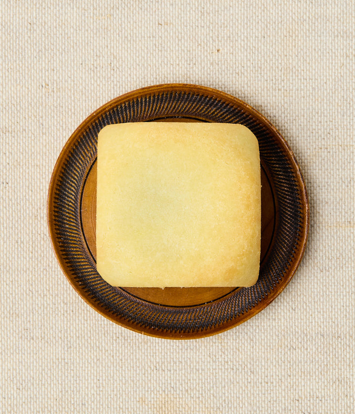 Top view of a square Taiwanese pineapple cake on a brown patterned plate.