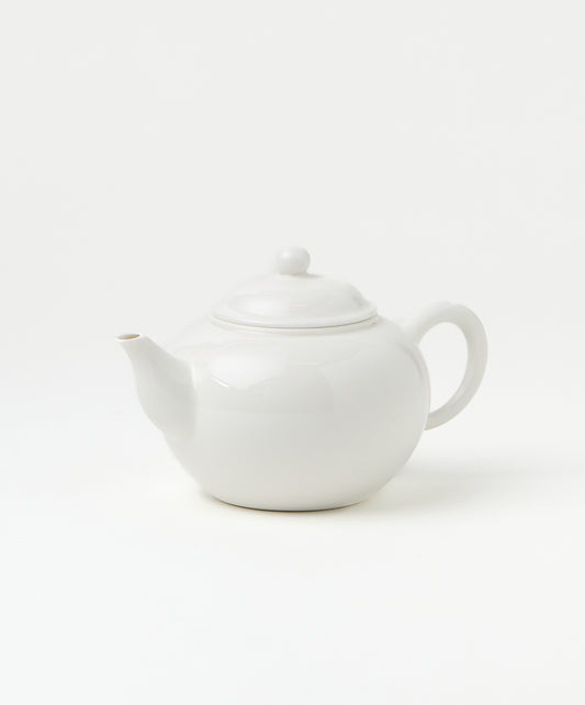 Side view of a white porcelain teapot with a smooth, rounded body, a curved spout, and a loop handle.