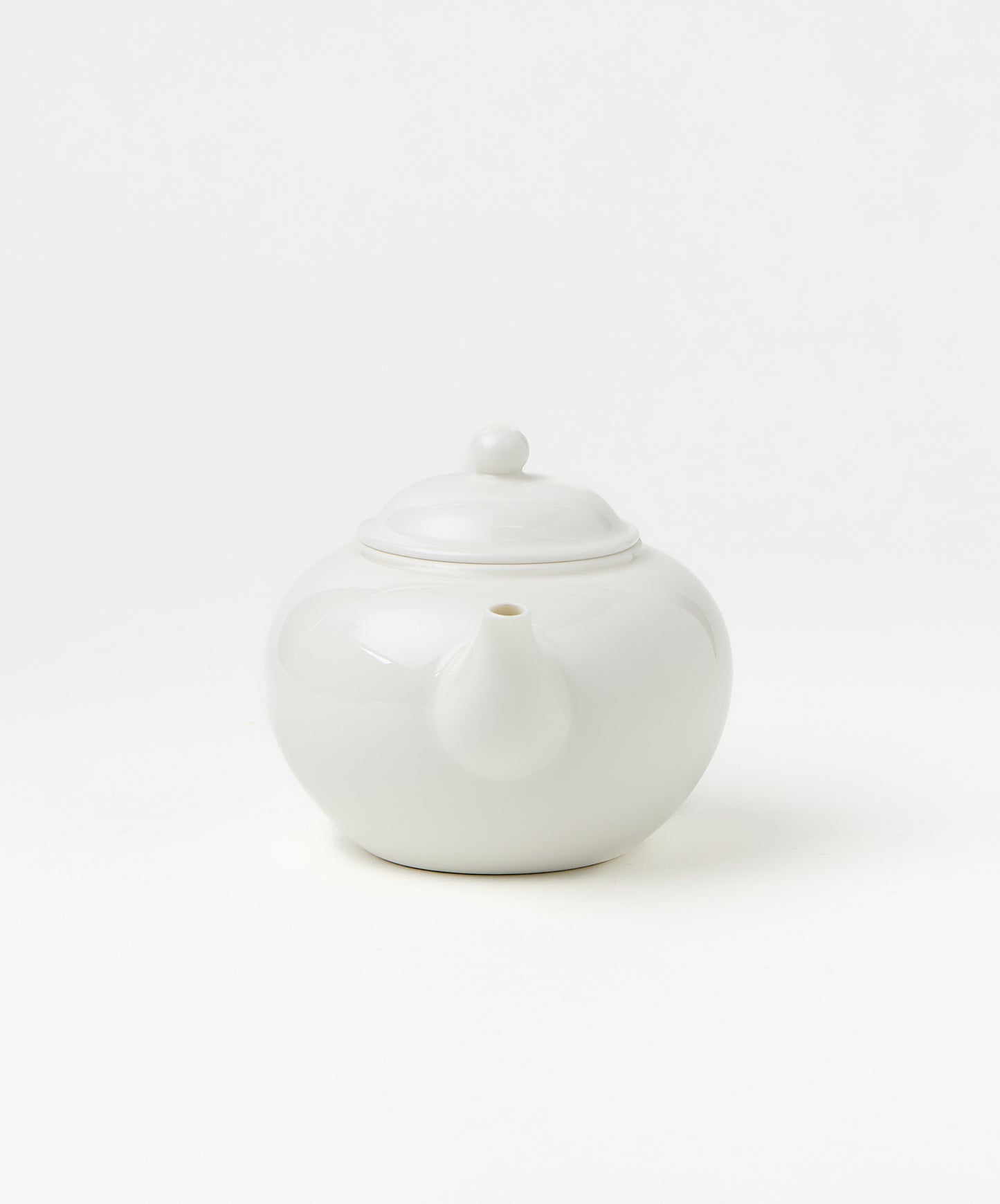 Front view of a white porcelain teapot showing its spout and lid.