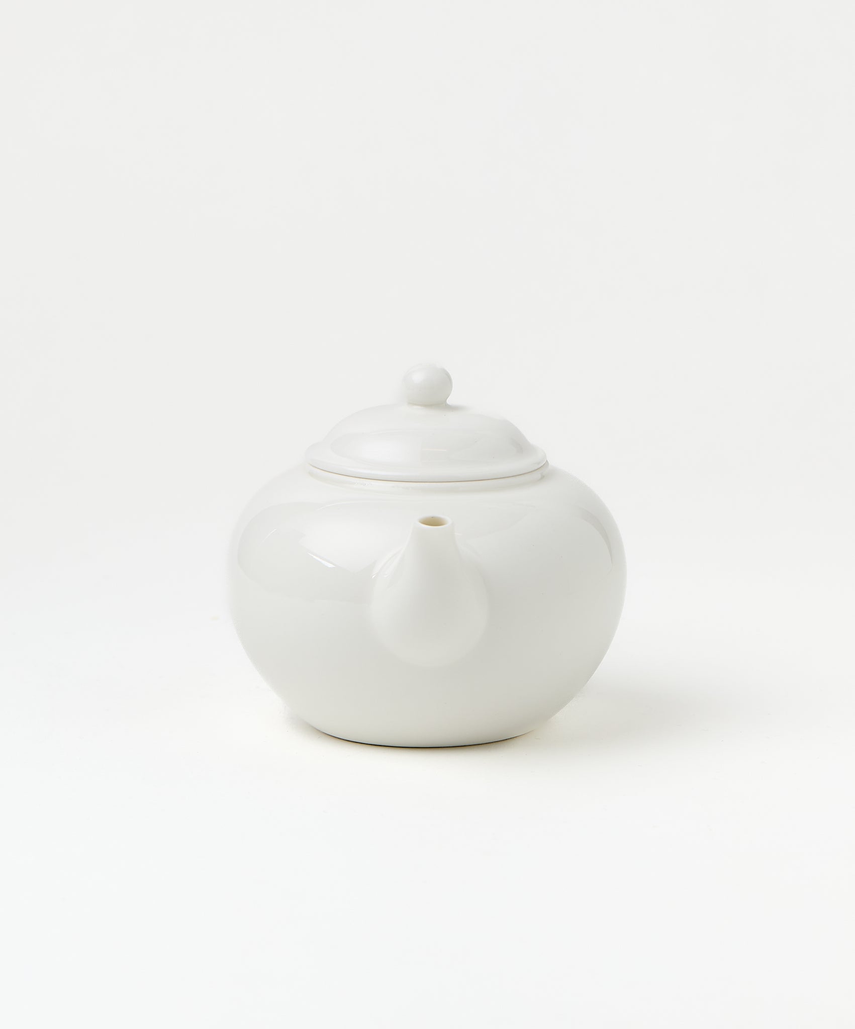 Front view of a white porcelain teapot showing its spout and lid.