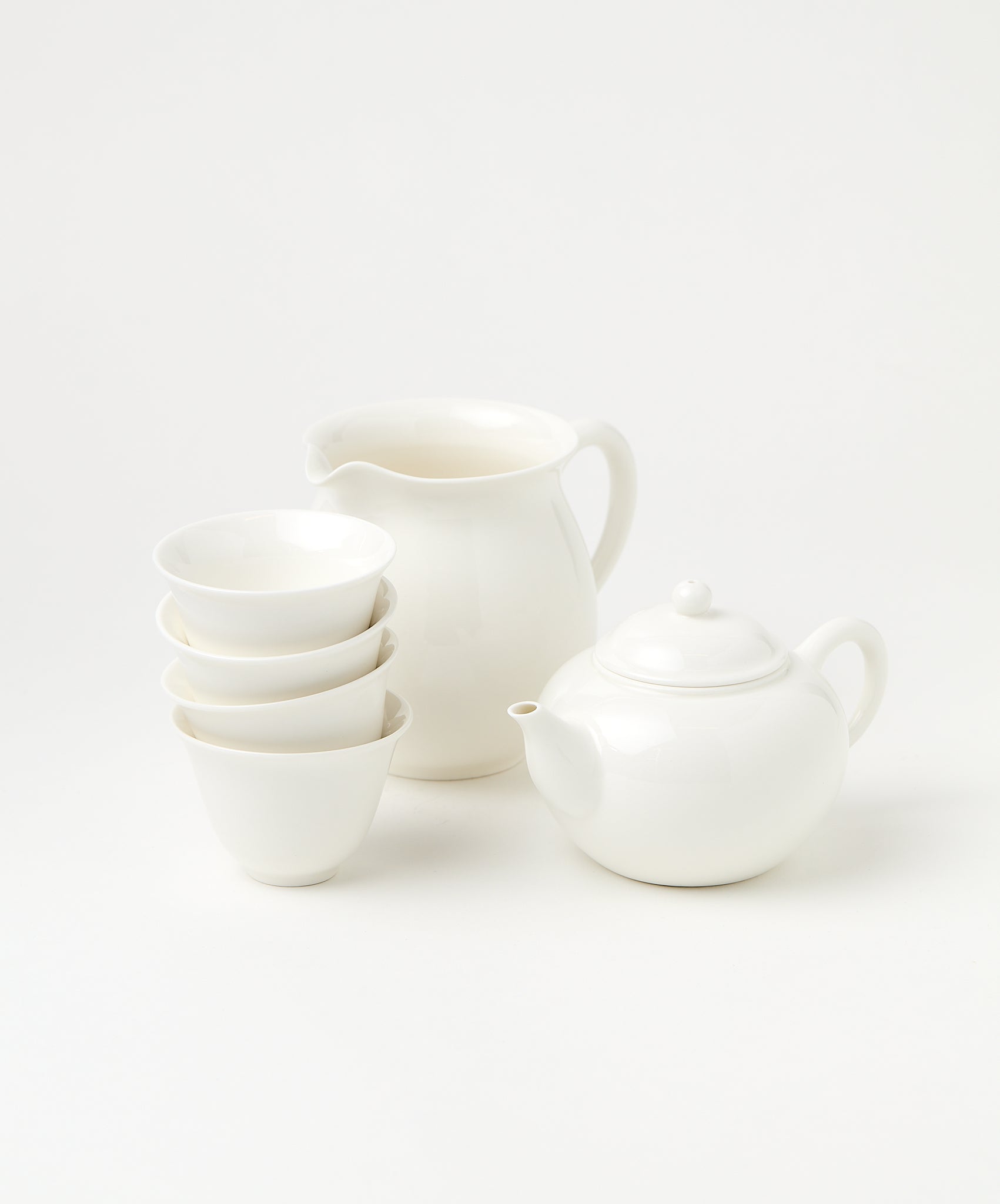 A porcelain brewing set featuring a white teapot, pitcher, and four stacked cups.