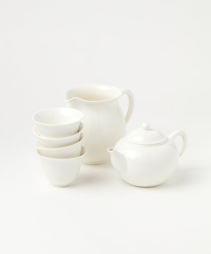 A porcelain brewing set featuring a white teapot, pitcher, and four stacked cups.