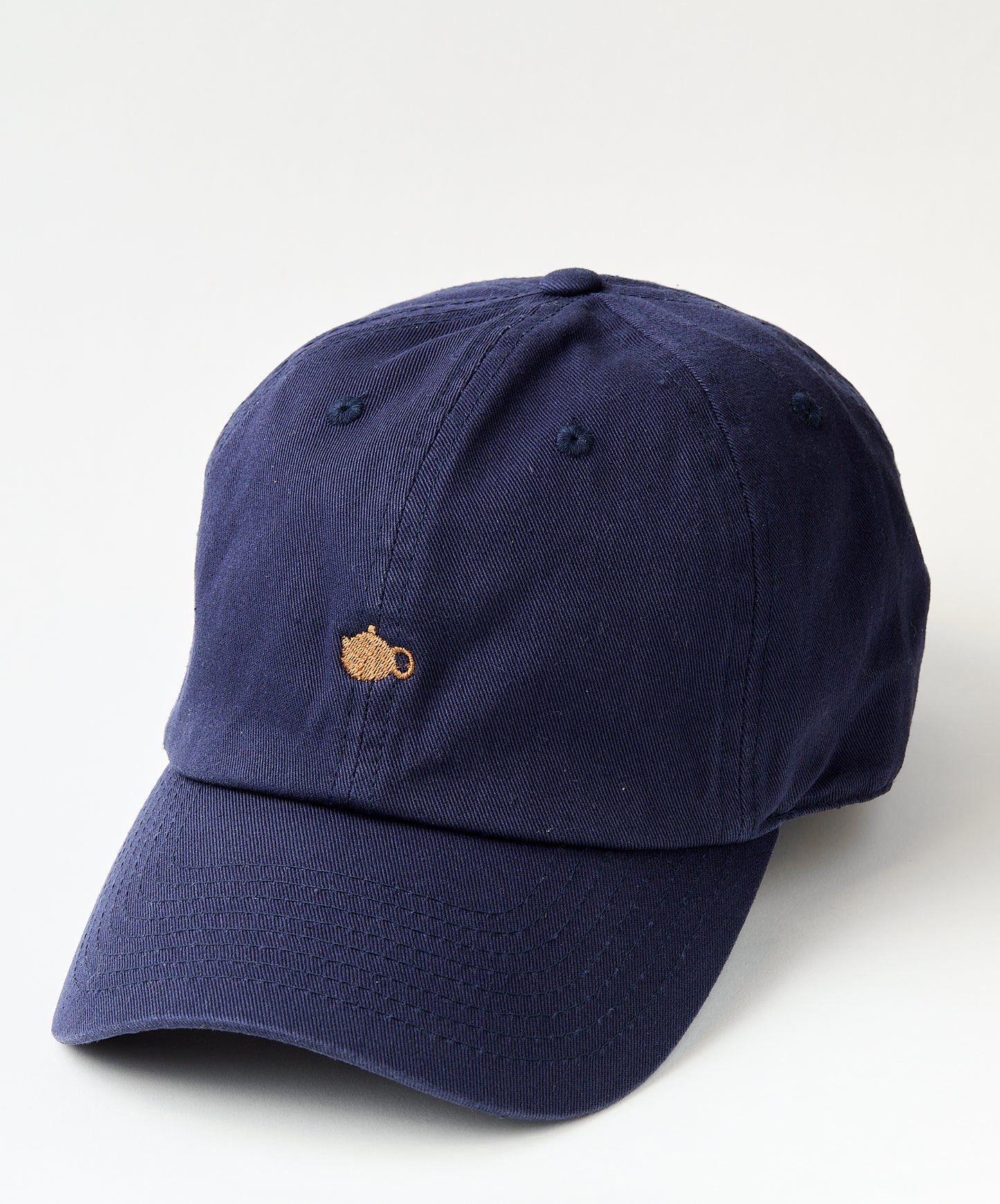 Navy blue baseball cap with a small embroidered golden teapot design on the front.