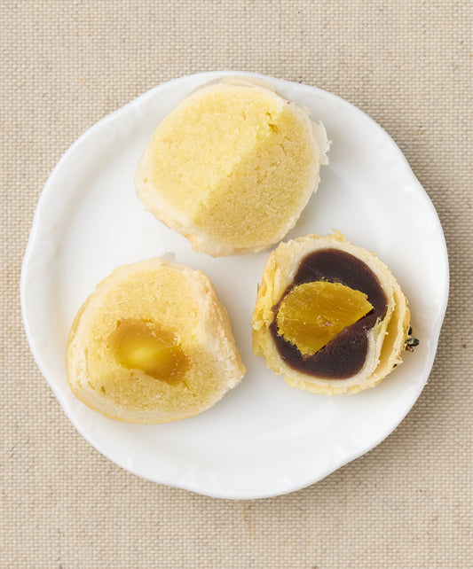 Three halved pastries on a white plate, showing yellow and dark brown fillings.