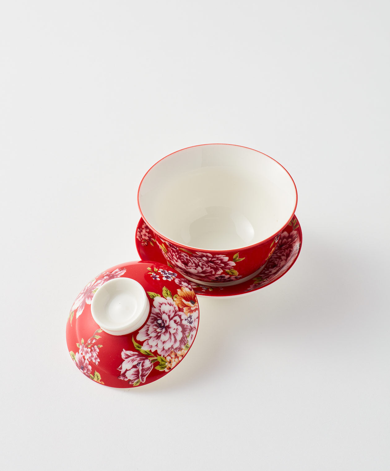 Open red floral gaiwan with saucer and lid nearby