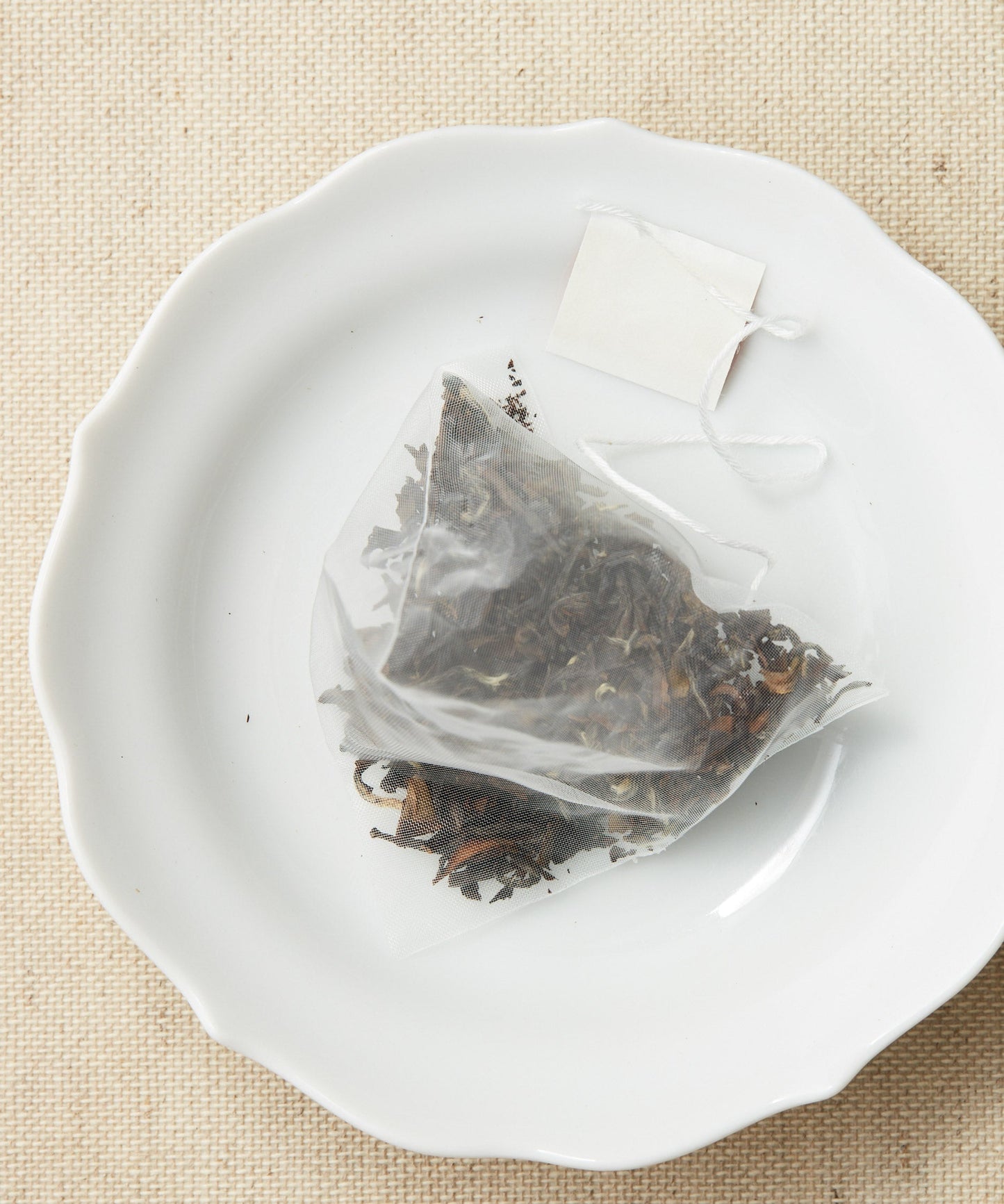 A pyramid-shaped tea sachet filled with dried leaves.