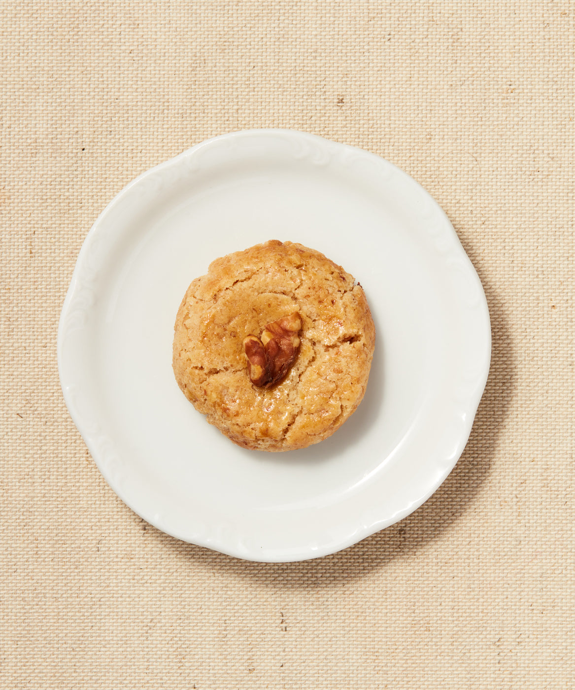 Single walnut-topped Button Cookie on a white plate.